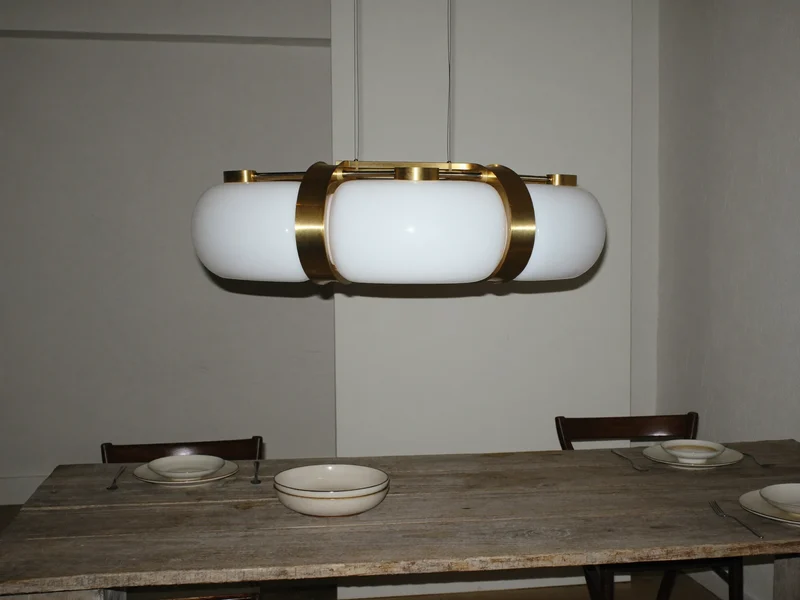 Suspension en laiton et verre opalin au-dessus d’une table en bois