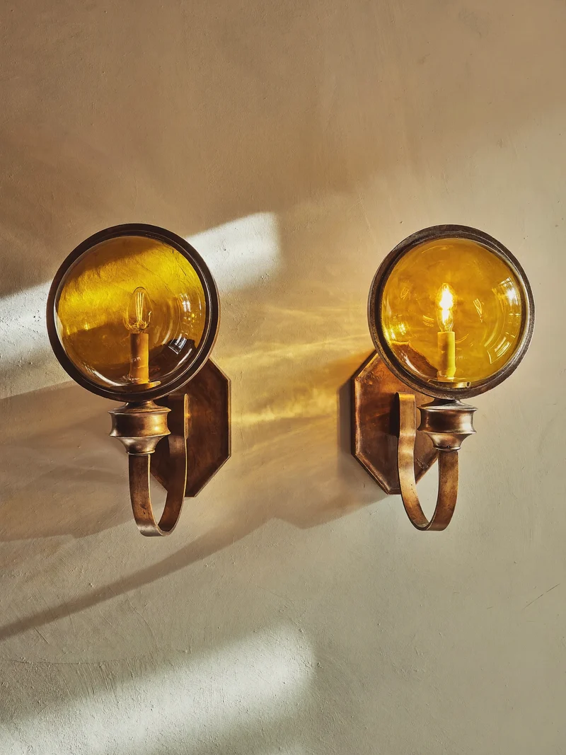 Deux appliques vintage à globes ambrés sur un mur en enduit crème
